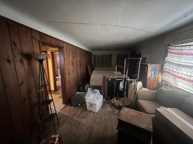 bedroom with wooden walls, wood-type flooring, and a textured ceiling