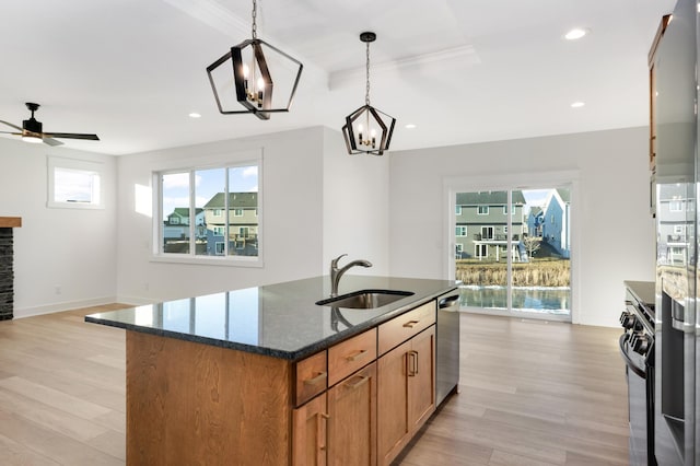 kitchen featuring sink, stainless steel appliances, dark stone counters, pendant lighting, and light wood-type flooring