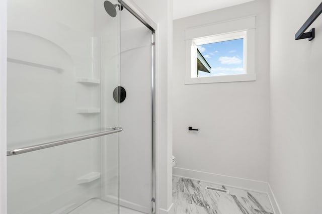 bathroom featuring toilet and a shower with door