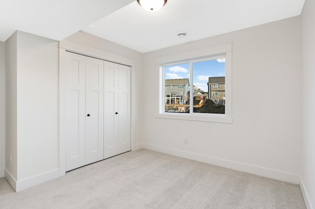 unfurnished bedroom with light carpet and a closet