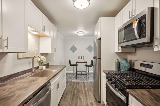 kitchen featuring white cabinets, appliances with stainless steel finishes, butcher block countertops, and sink