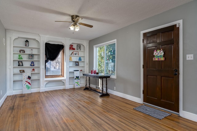 foyer entrance featuring ceiling fan, wood-type flooring, and a textured ceiling