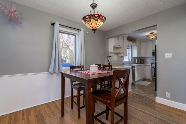 dining area with sink, wood-type flooring, and a textured ceiling