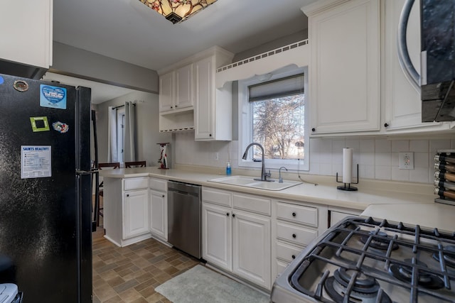 kitchen with black fridge, sink, white cabinets, and stainless steel dishwasher