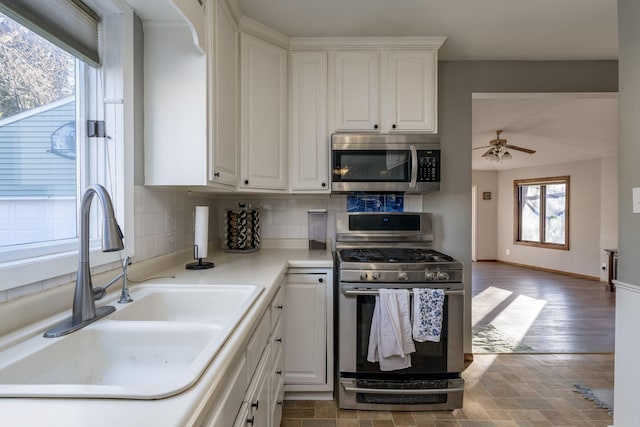 kitchen with sink, ceiling fan, appliances with stainless steel finishes, tasteful backsplash, and white cabinetry