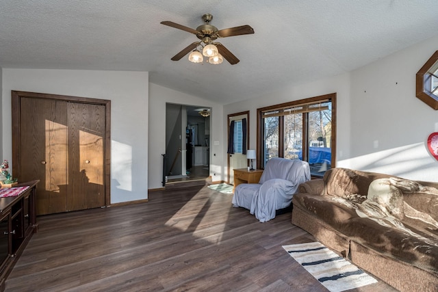 living room with dark hardwood / wood-style floors, ceiling fan, lofted ceiling, and a textured ceiling