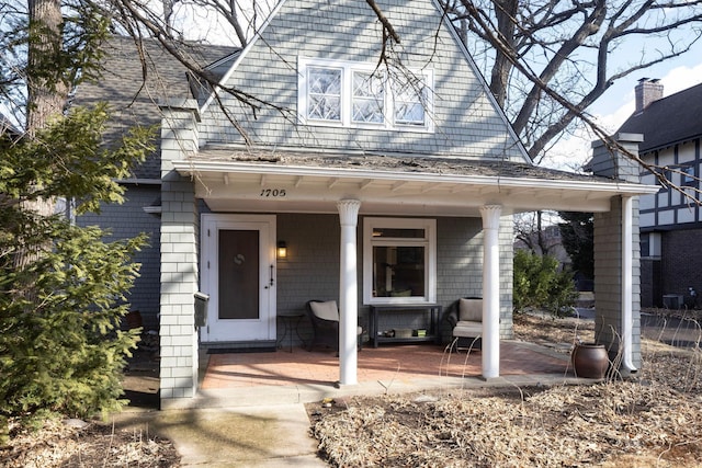 property entrance with central air condition unit, a shingled roof, and a porch