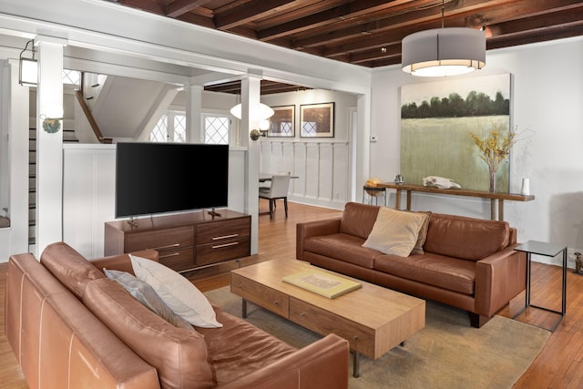 living room featuring stairs, beam ceiling, a decorative wall, and hardwood / wood-style flooring