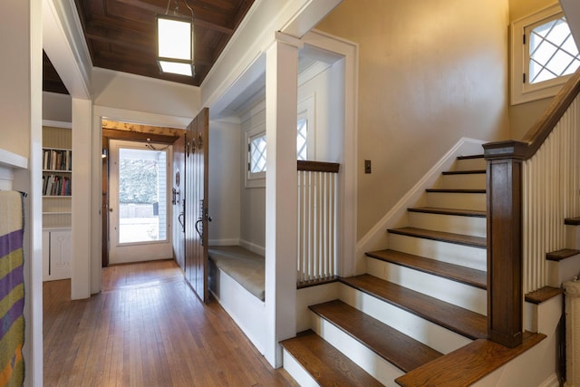 entryway featuring stairs, baseboards, ornate columns, and hardwood / wood-style flooring