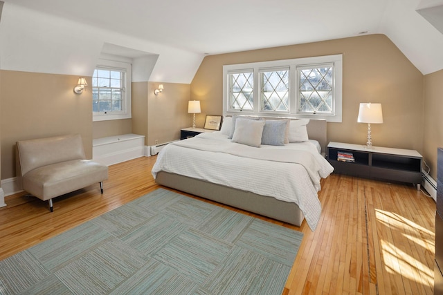 bedroom with lofted ceiling, light wood-style floors, and baseboards