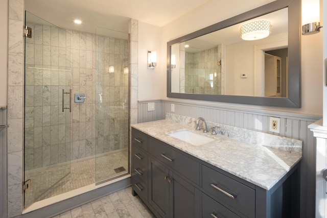 bathroom featuring a shower stall, vanity, and wainscoting