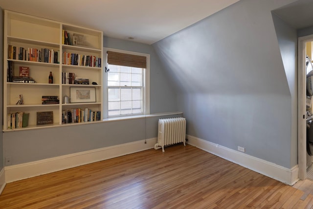 additional living space with radiator, vaulted ceiling, baseboards, and wood finished floors