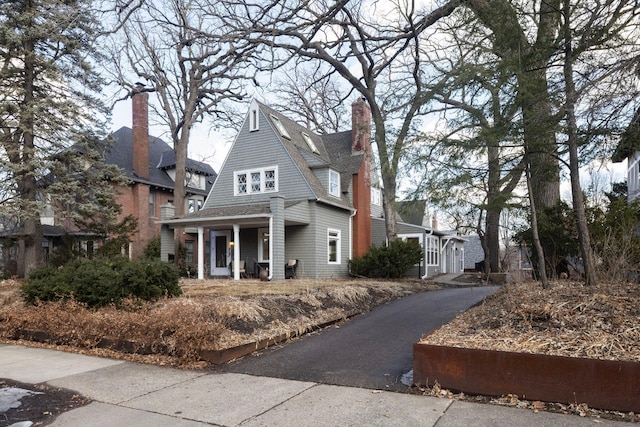 view of front facade with a shingled roof and a chimney