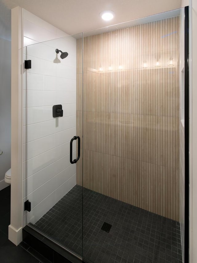 bathroom with tile patterned flooring, an enclosed shower, and toilet