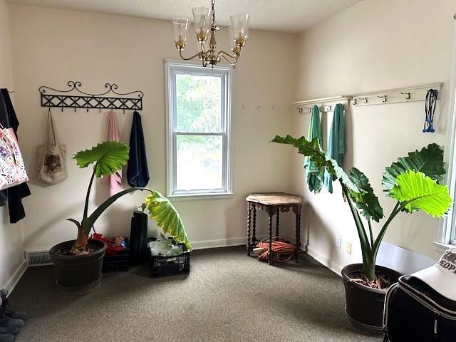 miscellaneous room featuring carpet and an inviting chandelier