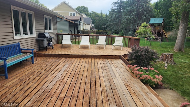 wooden deck with a yard, grilling area, and a playground