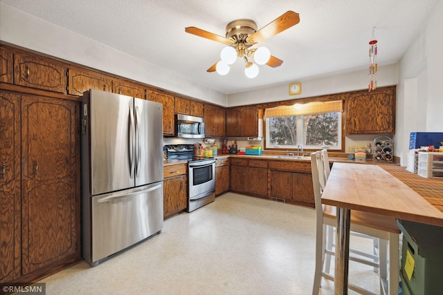 kitchen featuring ceiling fan, appliances with stainless steel finishes, sink, and a textured ceiling