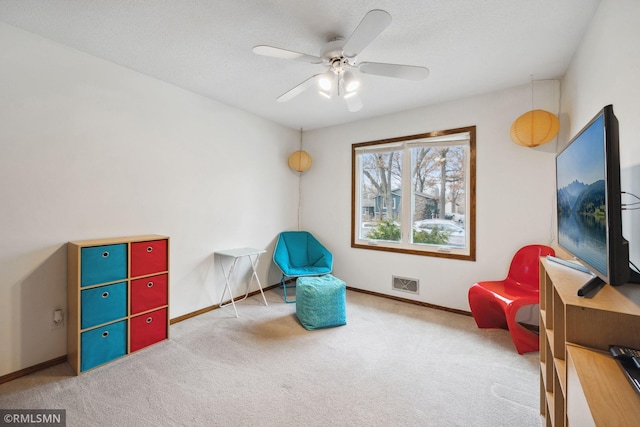 living area featuring carpet flooring, a textured ceiling, and ceiling fan