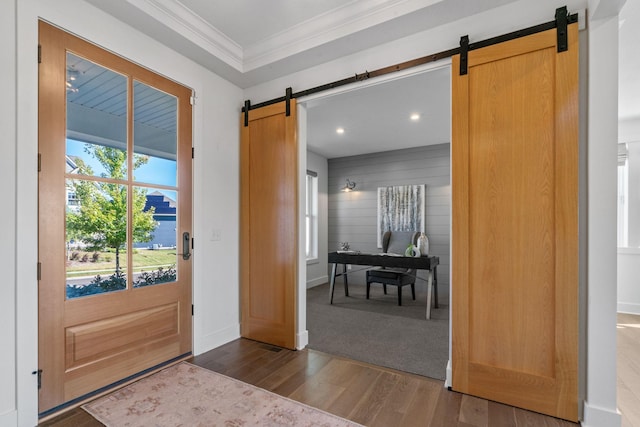 entrance foyer featuring ornamental molding, a barn door, and dark hardwood / wood-style floors