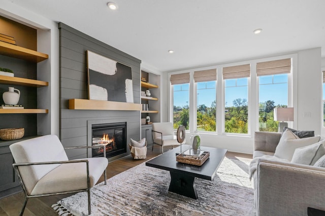 living room featuring built in shelves, a fireplace, and dark hardwood / wood-style flooring