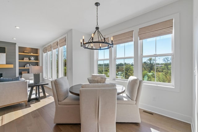 dining room with built in shelves, dark hardwood / wood-style floors, and an inviting chandelier