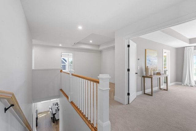 corridor with light carpet and a tray ceiling