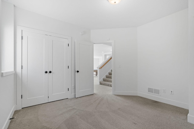 unfurnished bedroom with light colored carpet and a closet