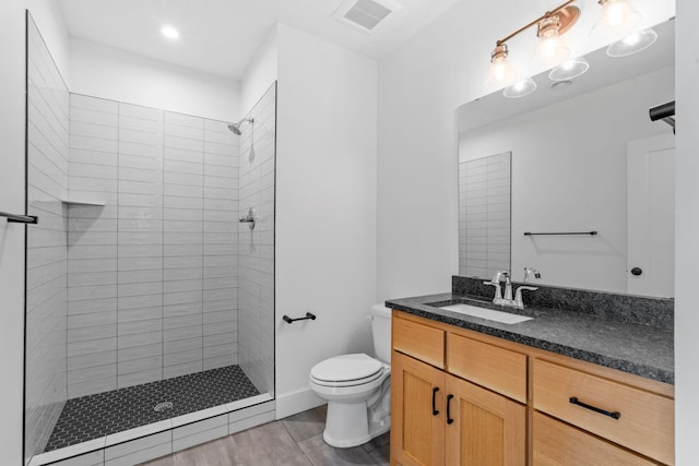 bathroom with vanity, hardwood / wood-style floors, toilet, and tiled shower