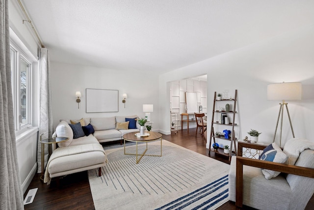 living room featuring visible vents, baseboards, and wood finished floors