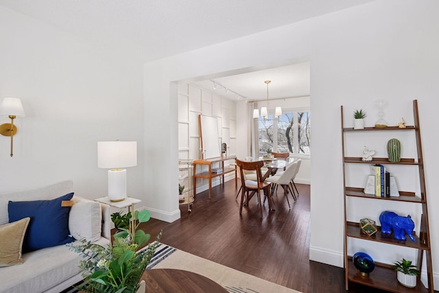 dining room with a chandelier, track lighting, baseboards, and wood finished floors