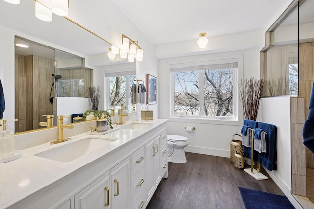 full bath with double vanity, toilet, wood finished floors, and a sink