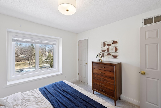 bedroom featuring a textured ceiling, baseboards, visible vents, and light carpet