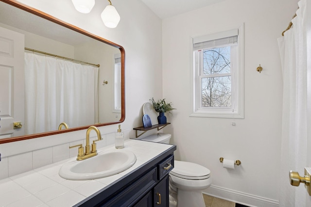 bathroom with vanity, toilet, baseboards, and tile patterned flooring