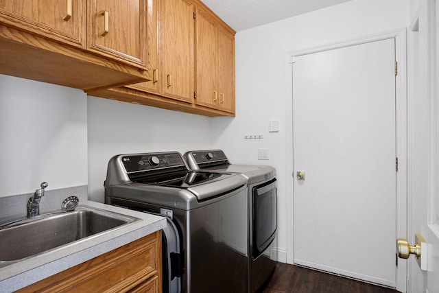 clothes washing area with dark wood-style floors, a sink, cabinet space, and separate washer and dryer