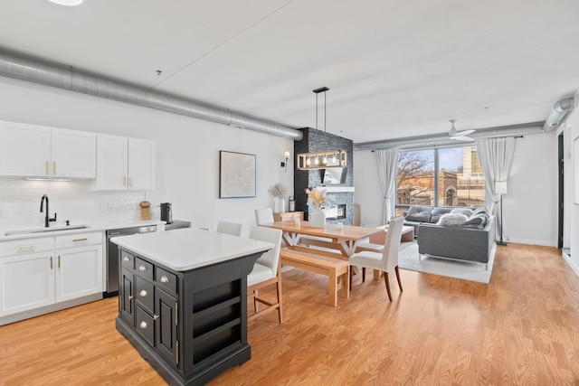 kitchen with backsplash, sink, dishwasher, white cabinetry, and hanging light fixtures