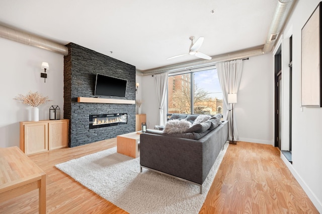 living room with ceiling fan, a fireplace, and light hardwood / wood-style flooring