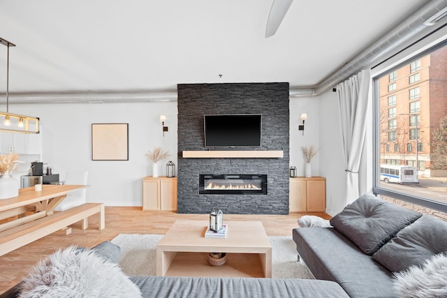 living room featuring ceiling fan, a fireplace, and light hardwood / wood-style floors