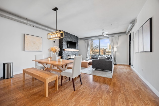 dining area featuring ceiling fan, a fireplace, and light hardwood / wood-style floors