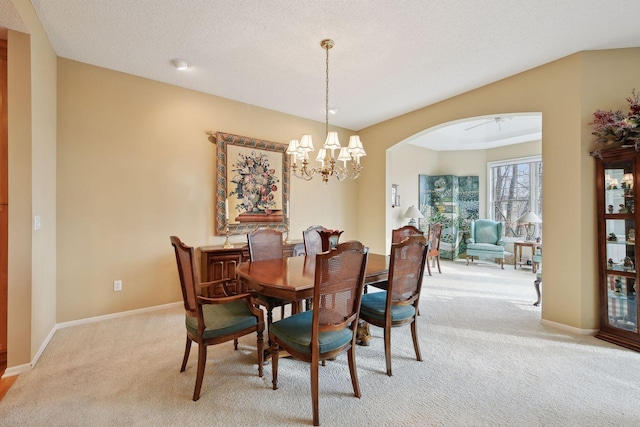 dining area featuring light colored carpet, a textured ceiling, and a notable chandelier