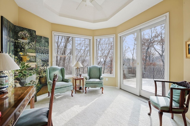 sunroom featuring a tray ceiling, ceiling fan, and a healthy amount of sunlight