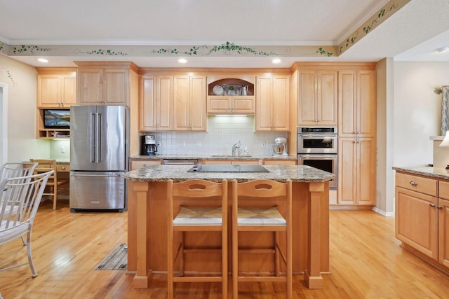 kitchen featuring light stone counters, a kitchen island, light wood-type flooring, and appliances with stainless steel finishes