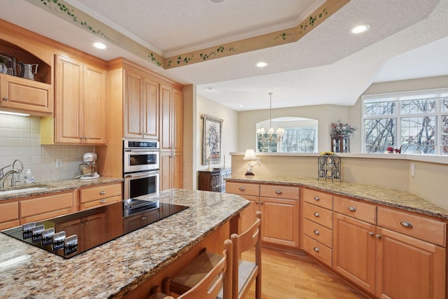 kitchen with light stone counters, a textured ceiling, sink, pendant lighting, and a notable chandelier