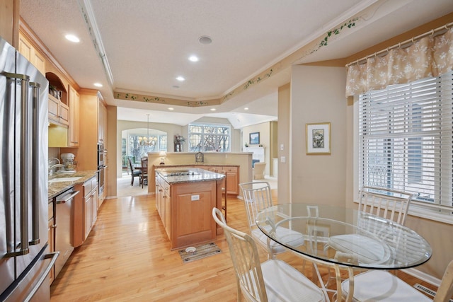 kitchen with kitchen peninsula, stainless steel appliances, a healthy amount of sunlight, a kitchen island, and hanging light fixtures