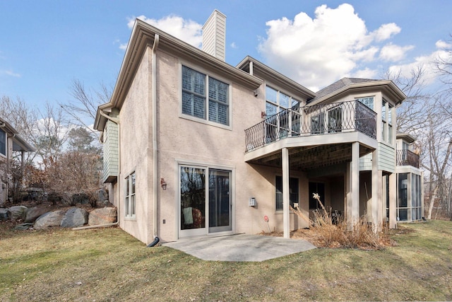 rear view of property featuring a lawn, a patio area, and a balcony