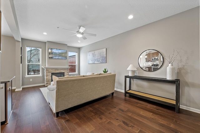 living room featuring dark hardwood / wood-style flooring, ceiling fan, and a fireplace