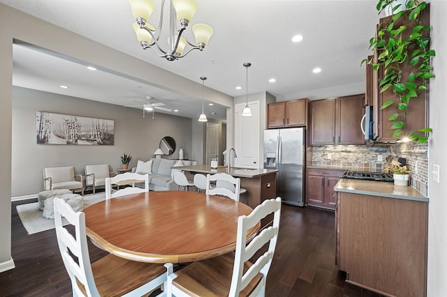 dining room with sink, dark hardwood / wood-style floors, and ceiling fan with notable chandelier