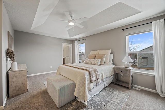 carpeted bedroom featuring a textured ceiling, ceiling fan, and a tray ceiling