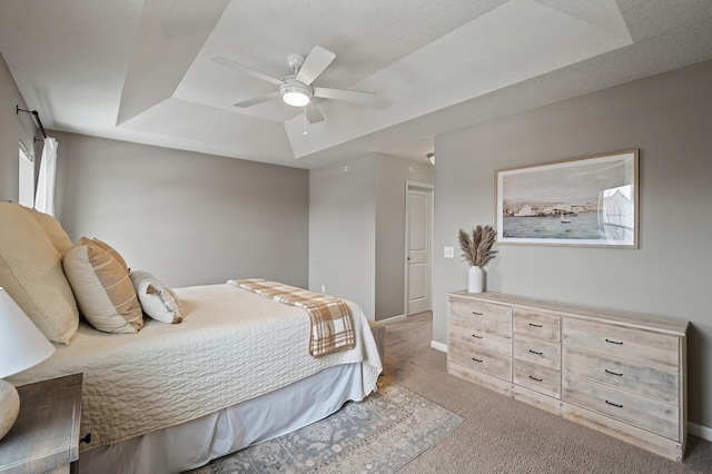 carpeted bedroom featuring ceiling fan and a raised ceiling