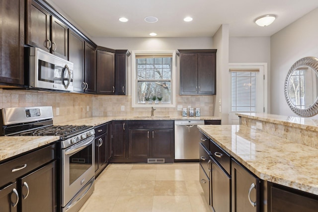 kitchen with stainless steel appliances, decorative backsplash, dark brown cabinetry, and sink