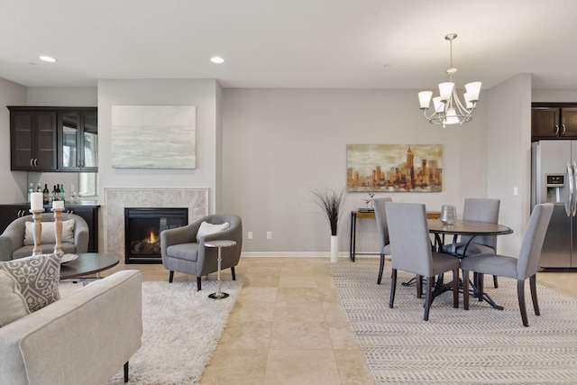 dining room with light tile patterned floors, a high end fireplace, and a chandelier